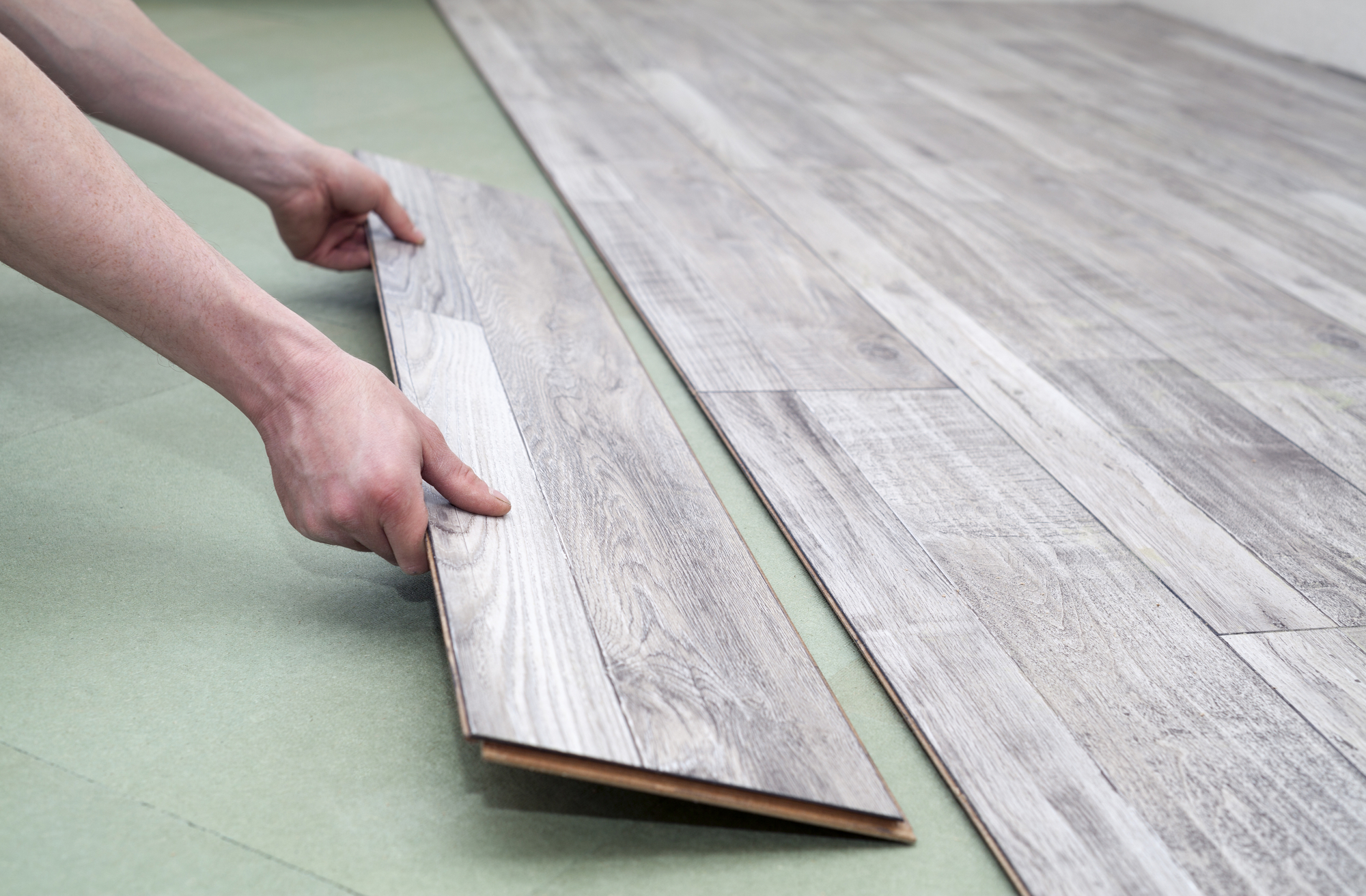 Close up of male hands installing new laminated flooring in room in Manchester